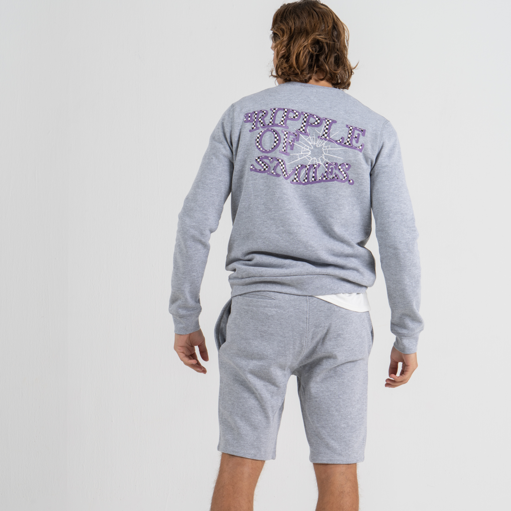 Man back wearing grey sweater SU1 clothing brand and grey shorts