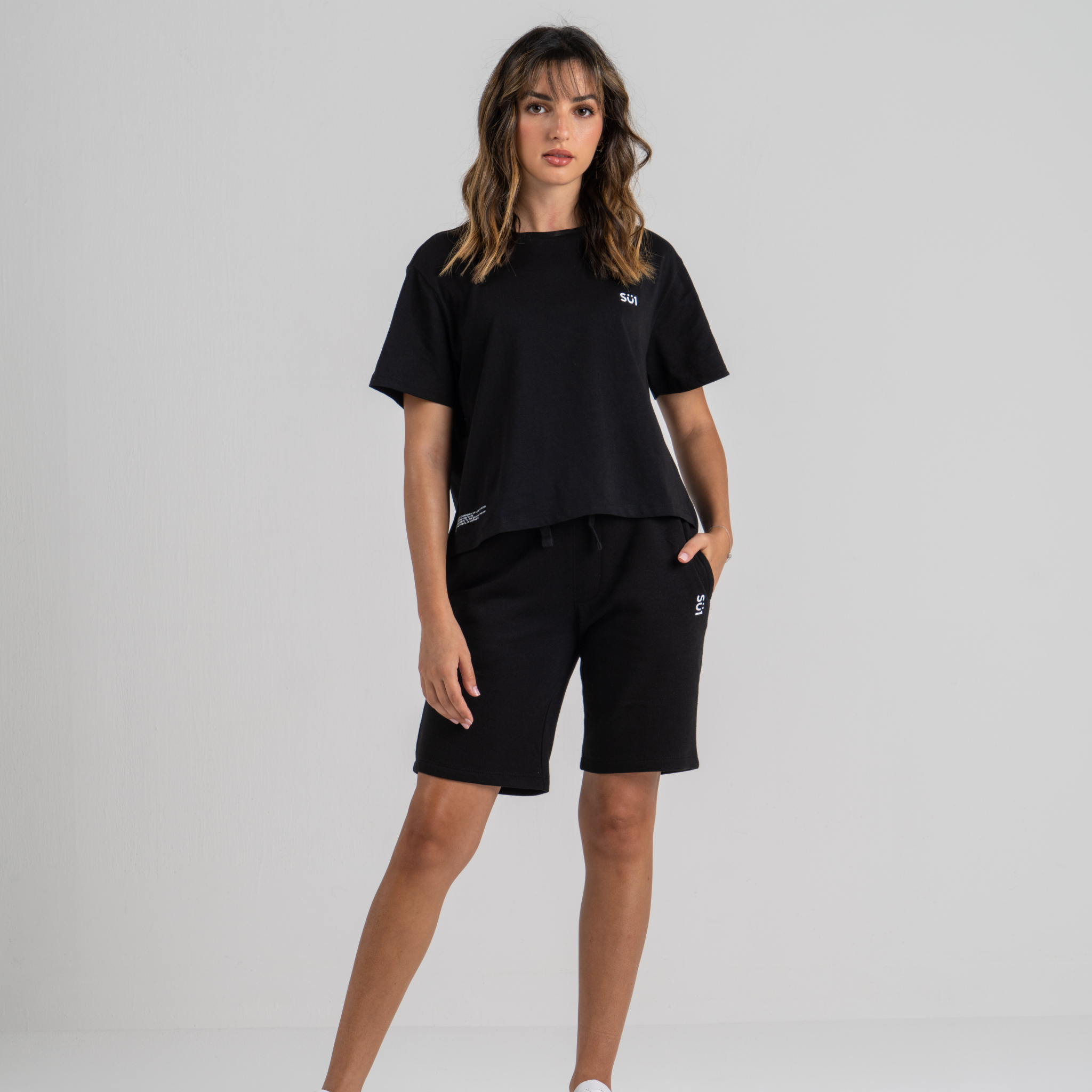 Woman wearing black mid crop tshirt and black shorts SU1 clothing brand