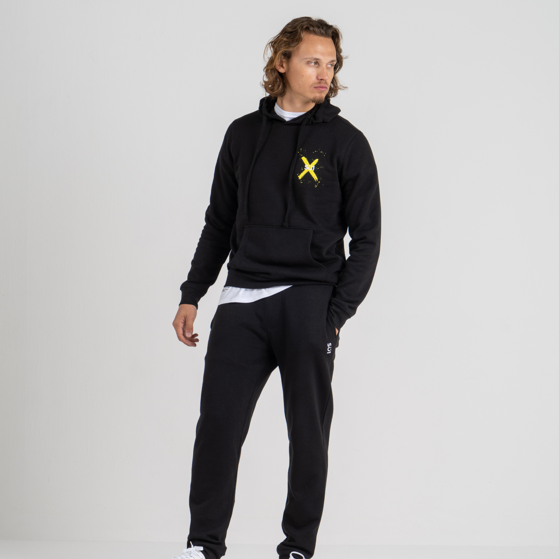 Man wearing black hoodie SU1 clothing brand and black sport trousers