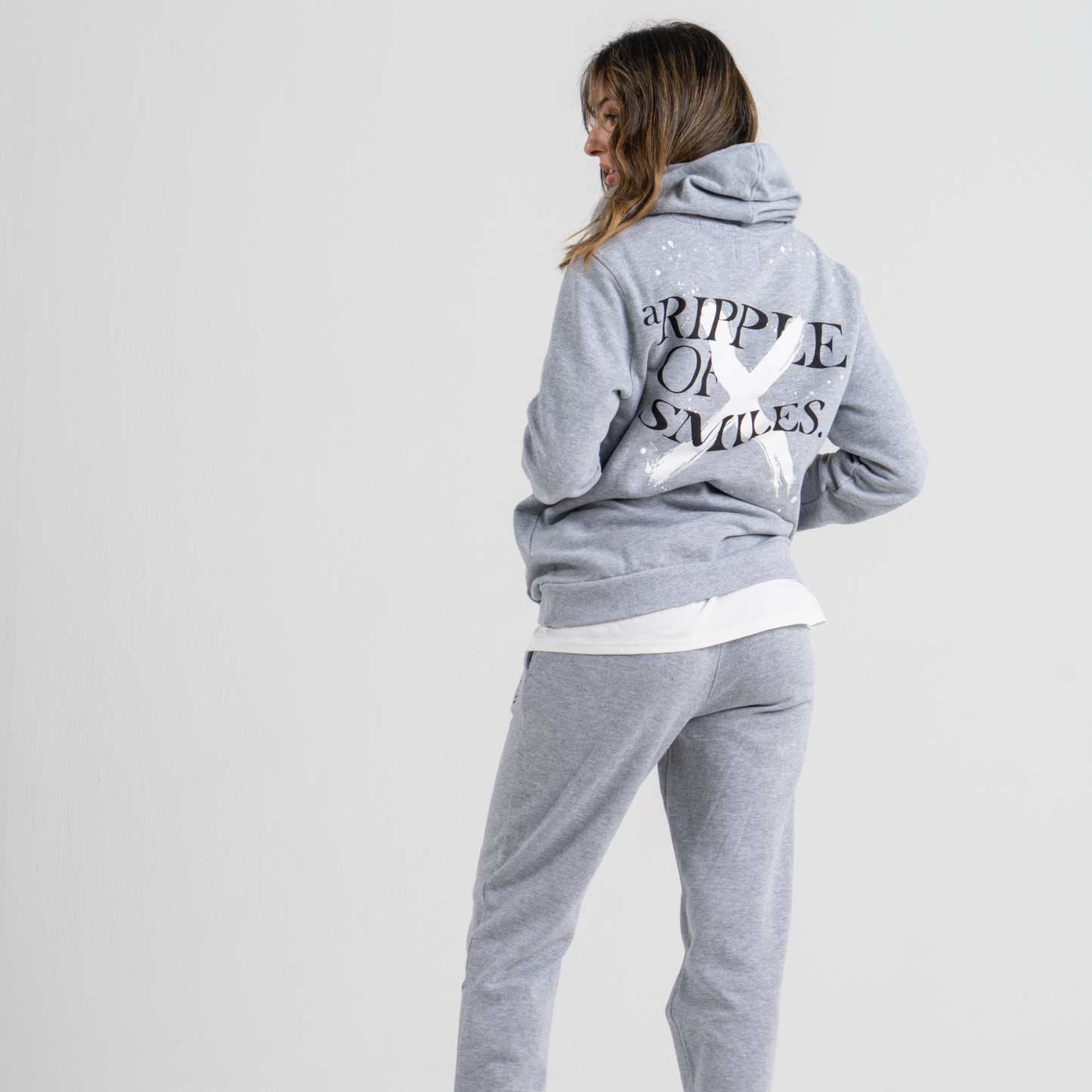 Woman back wearing grey hoodie SU1 clothing brand and grey sport trousers