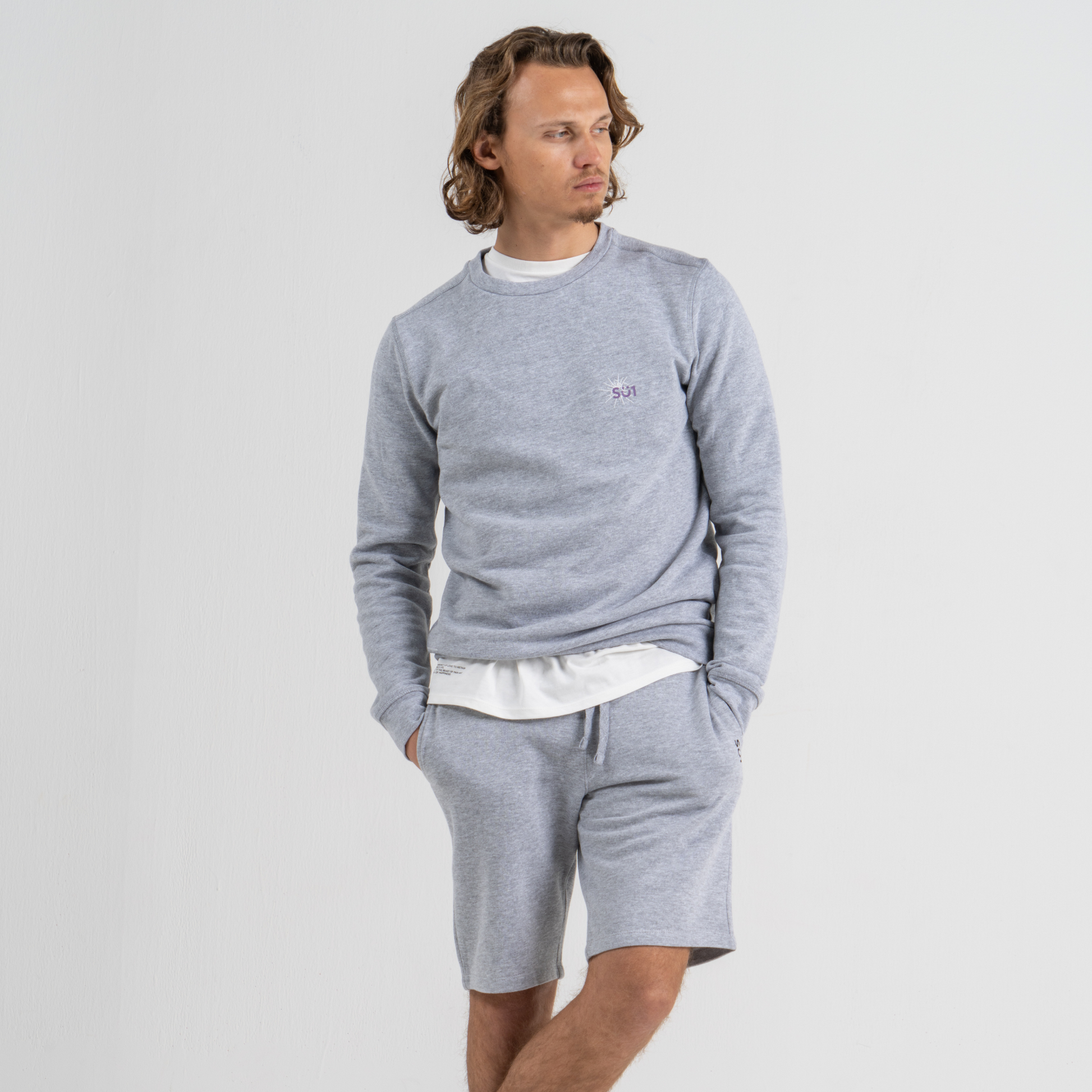Man wearing grey sweater SU1 clothing brand and grey shorts