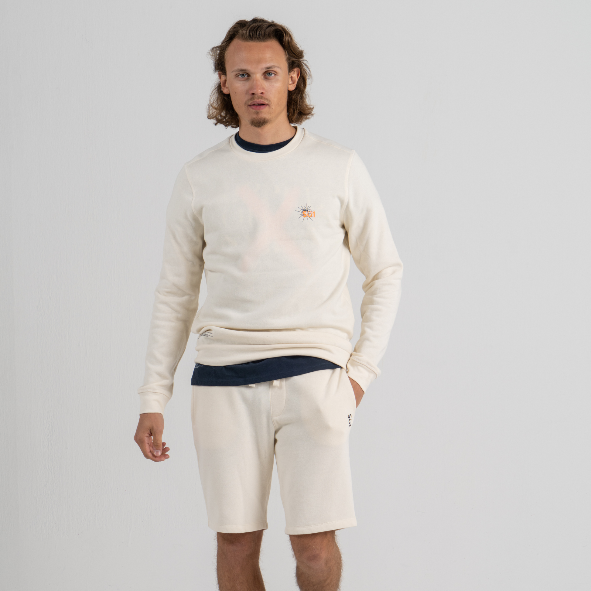 Man wearing ecru sweater SU1 clothing brand and ecru sport shorts