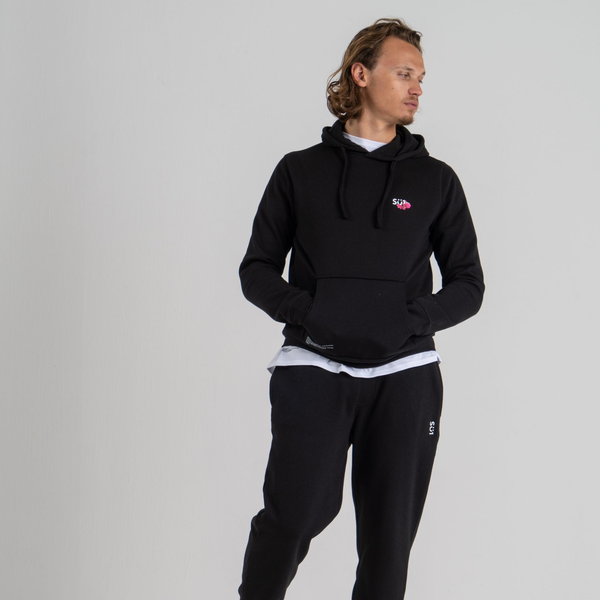 Man wearing black hoodie SU1 brand clothing and black sport trousers