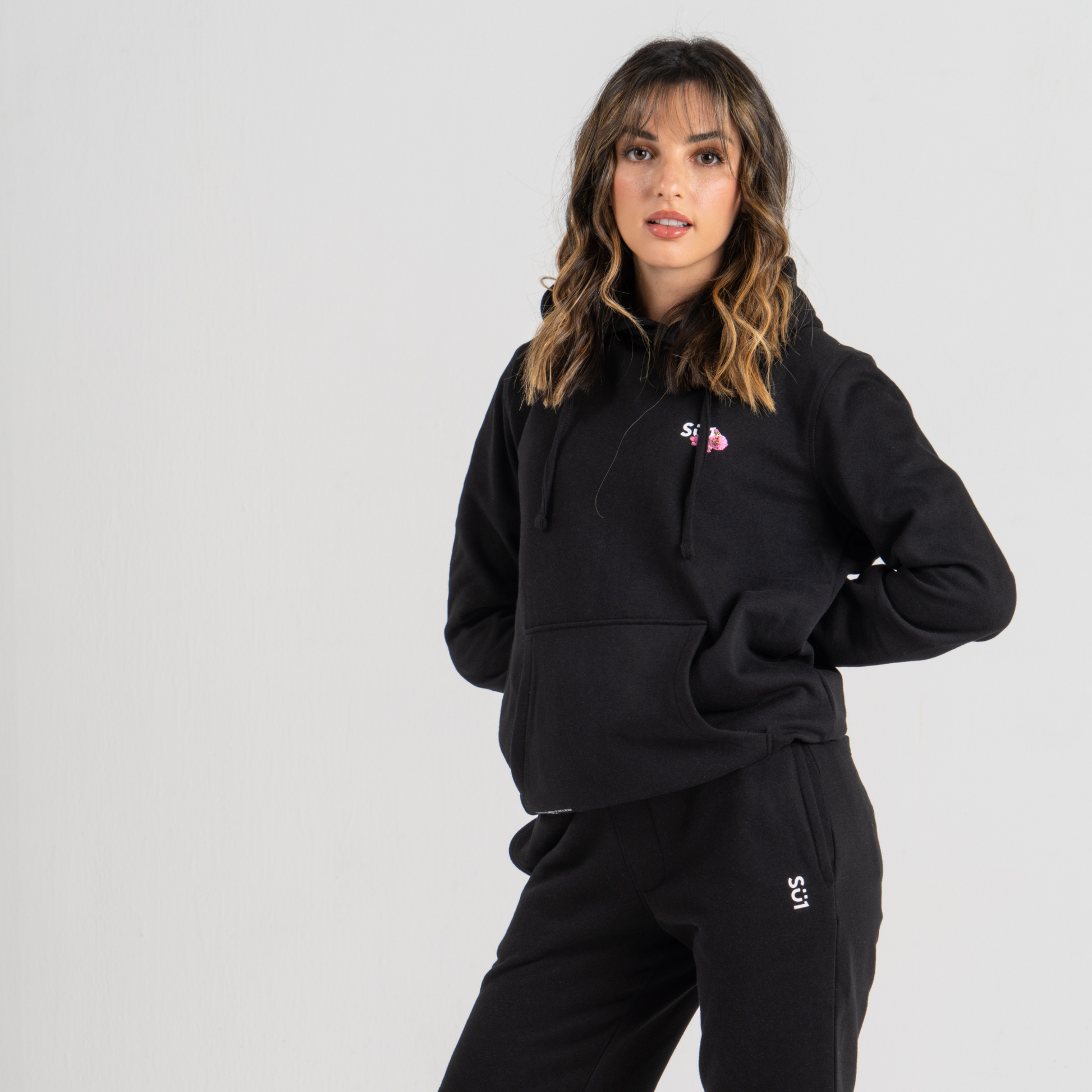 Woman wearing black hoodie SU1 brand clothing and black sport trousers