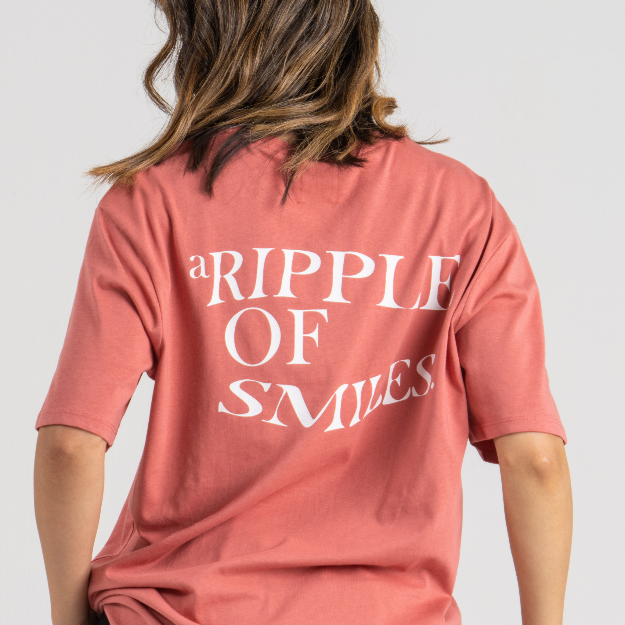 Woman back wearing pink tshirt oversized SU1 clothing brand